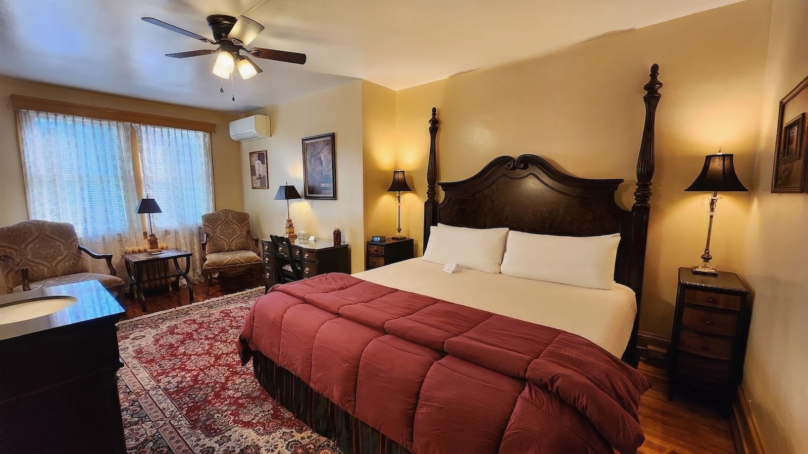 Yellow Room with cherry furniture and a king size, hardwood floor is accented by a couple of red and gold area rugs.
