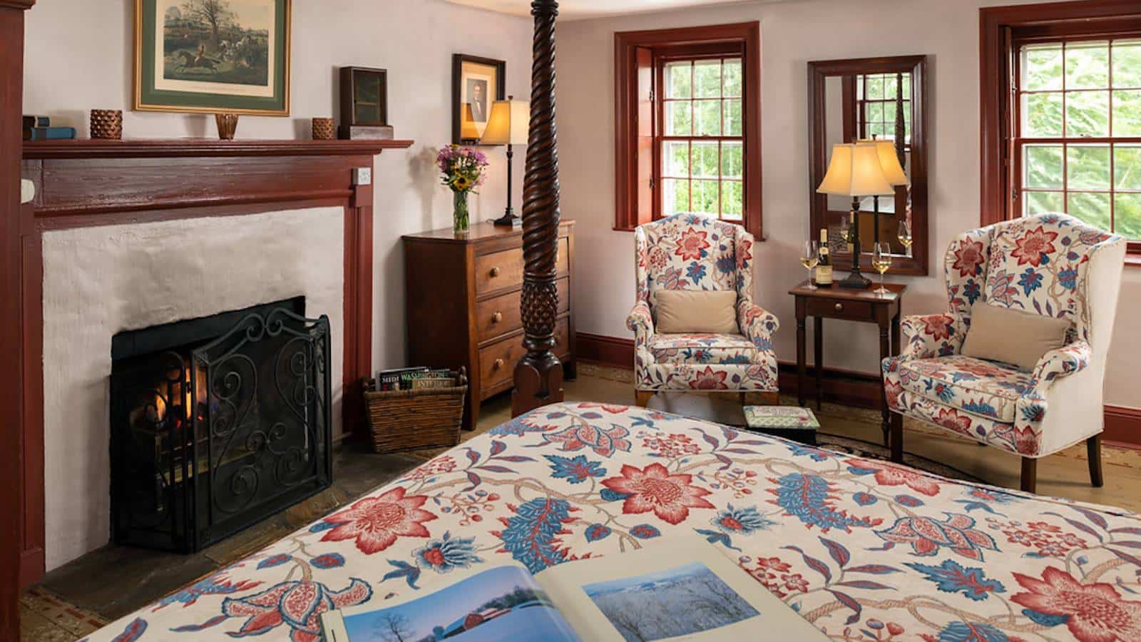 Bedroom with white walls, hardwood flooring, wooden trim, fireplace, and sitting area