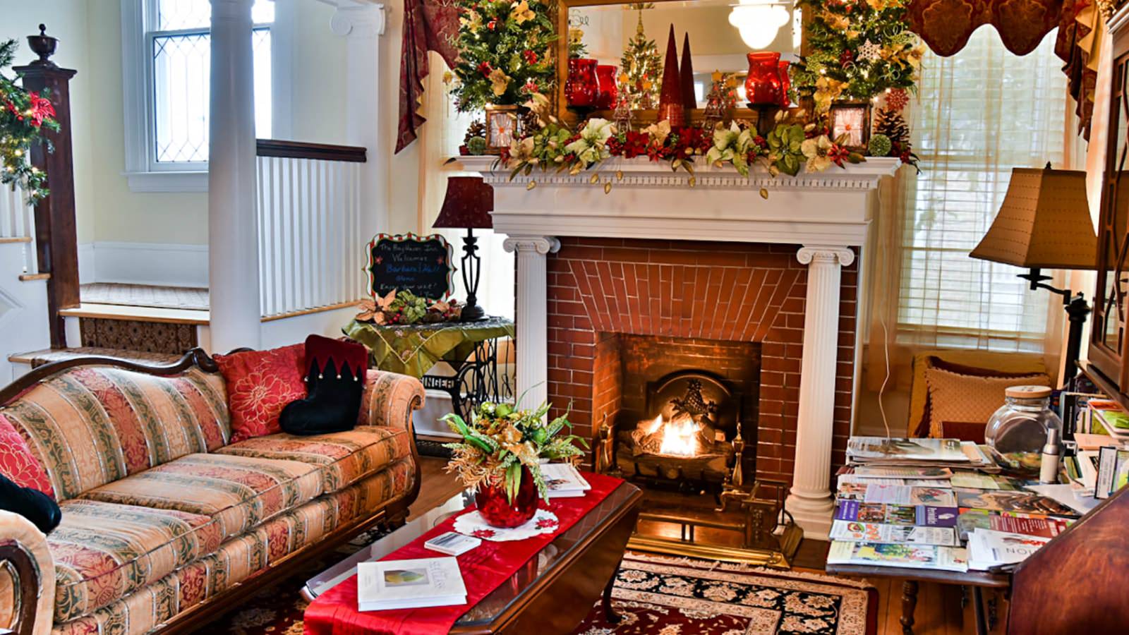 Living room with yellow walls, white trim, red brick fireplace, antique upholstered sofa, wooden coffee table, and antique desk