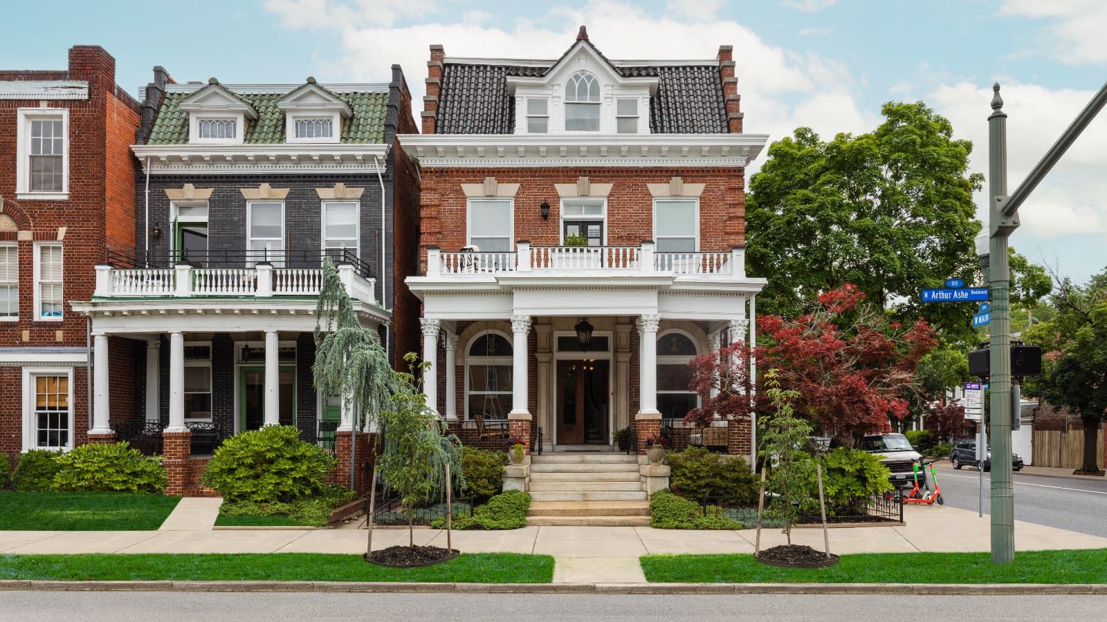 Exterior view of the property with red brick, white trim, front steps leading up to a porch, and second floor balcony