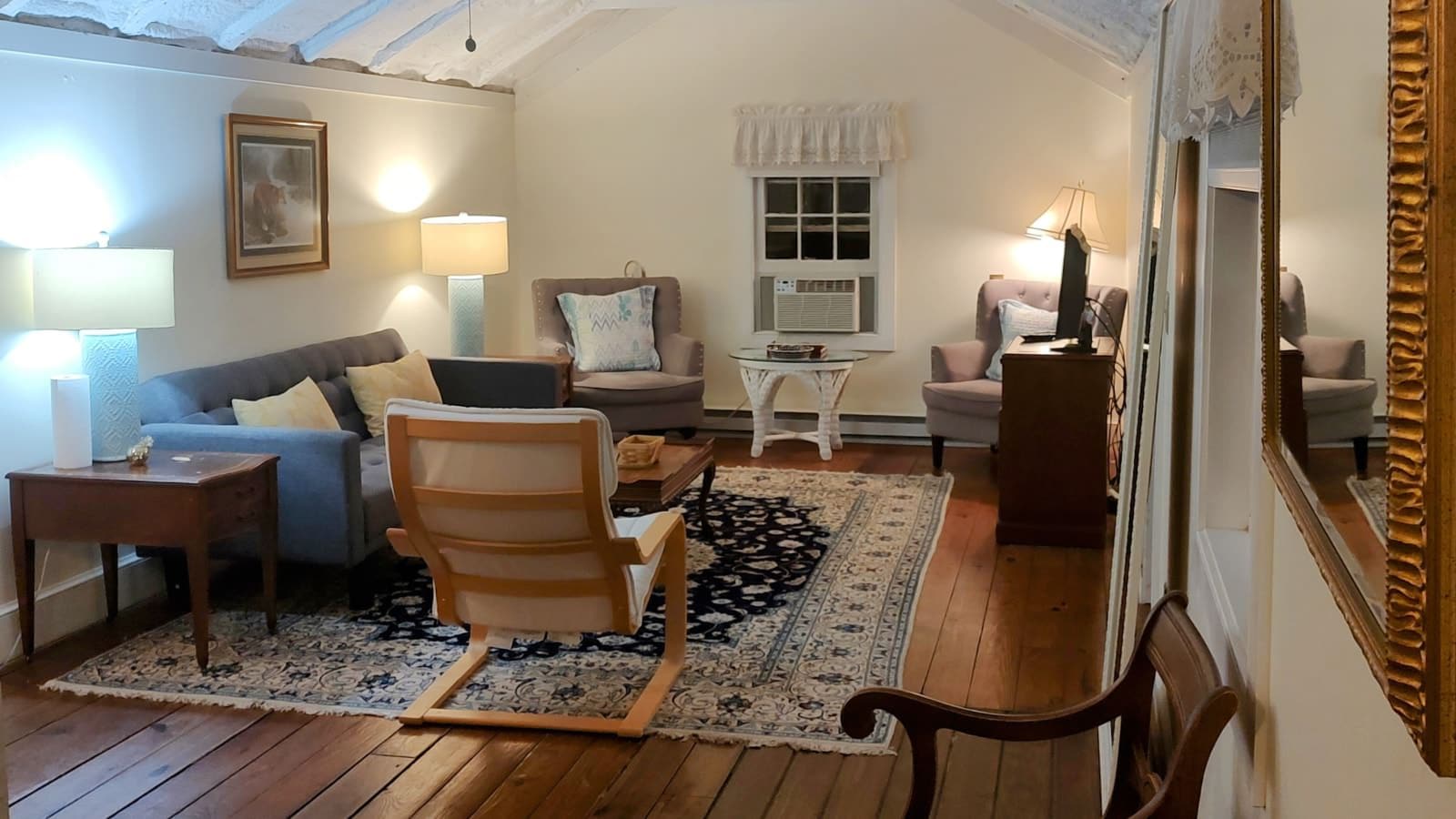 Living room with white walls, hardwood flooring, upholstered sofa, and sitting area