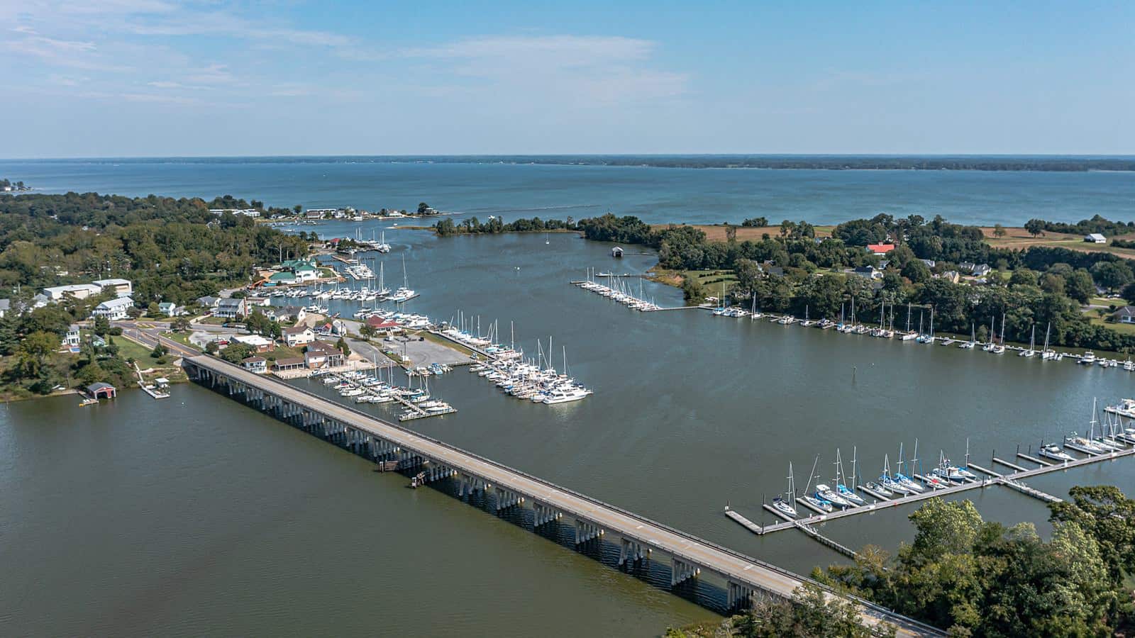 Aerial view of town near the water with multiple harbors and long highway bridge