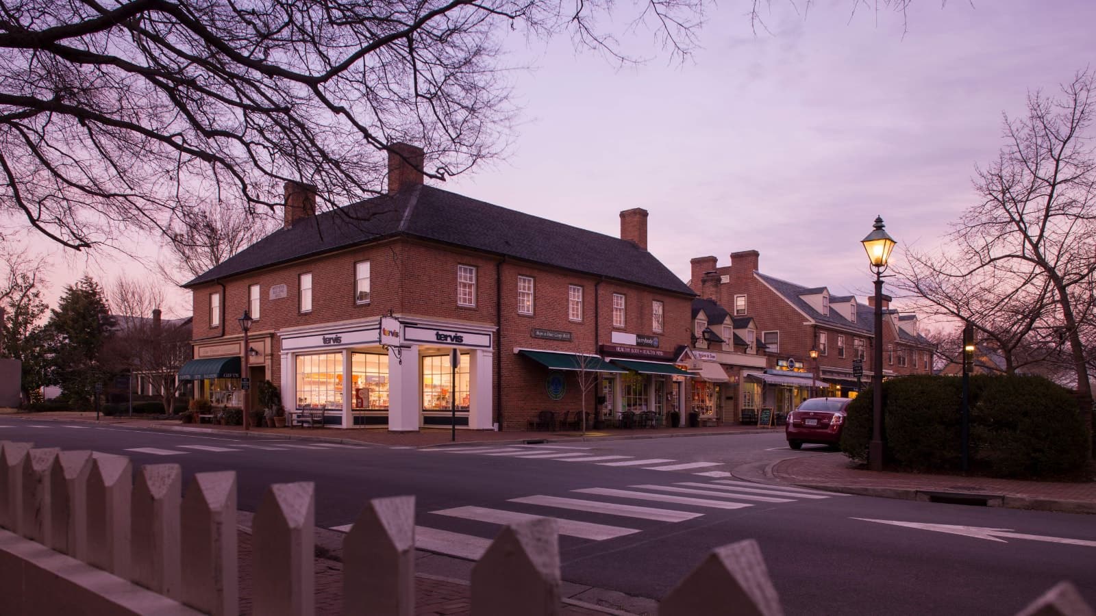 Exterior view of property with brown brick and light trim in a historic downtown area at dusk