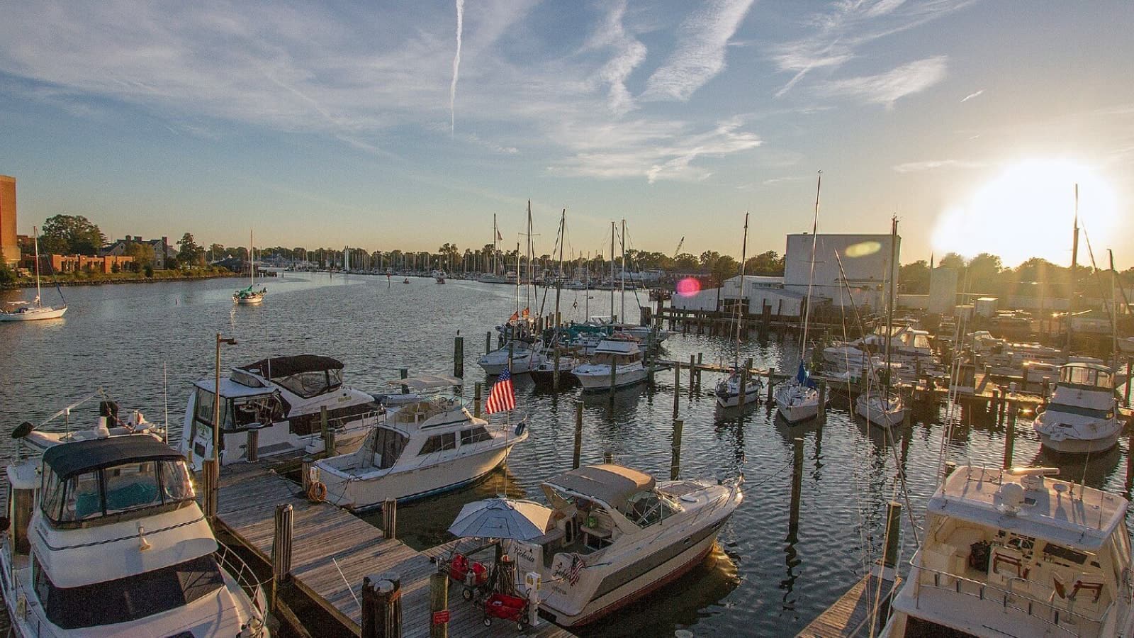 View of a marina with multiple small boats on calm water with a town near by