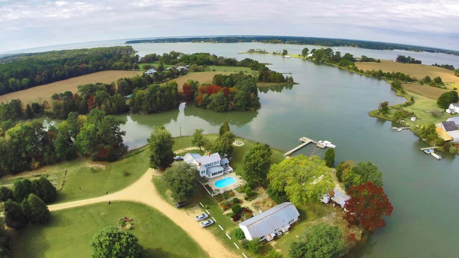 Aerial view of the property surrounded by green grass, trees, and water