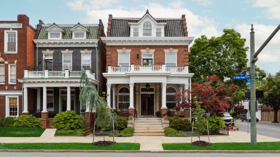 Exterior view of the property with red brick, white trim, front steps leading up to a porch, and second floor balcony